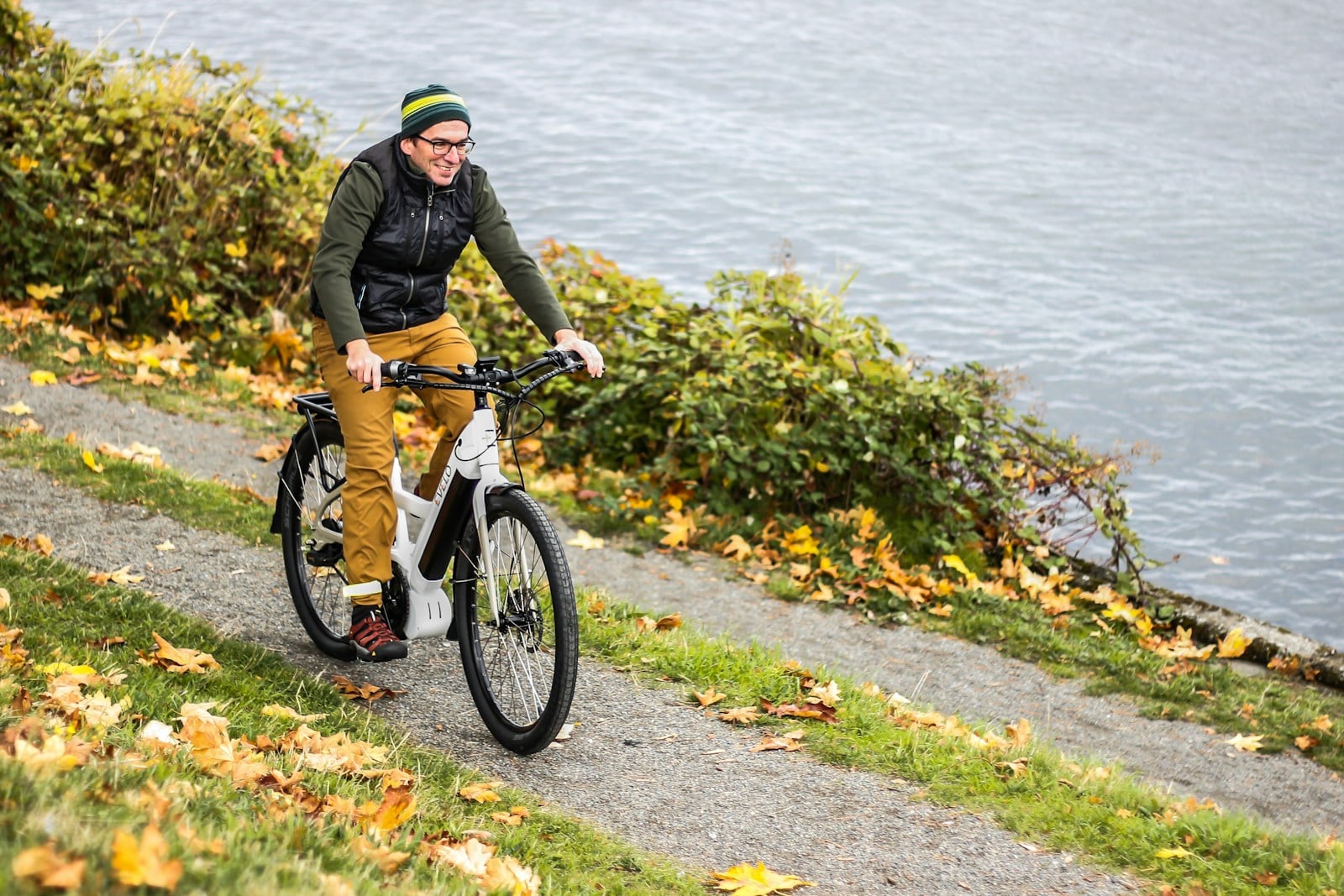 A rider on an e-bike on a lakeside path in autumn